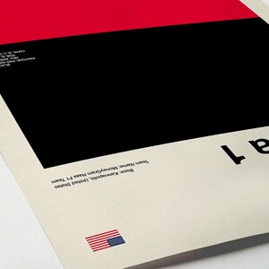 May include: A minimalist Formula 1 poster with a red and black color block design. The text "Formula 1" is displayed in black. The poster includes the text "Base: Kannapolis, United States" and "Team Name: MoneyGram Haas F1 Team". An American flag is also present.