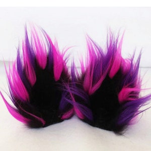 May include: Two fluffy black faux fur tail attachments with pink and purple streaks. The tails are designed to be sewn or clipped onto a costume or garment.