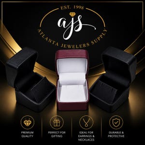 May include: Three jewelry boxes: two black and one burgundy. The burgundy box is open, revealing a white interior. The boxes are arranged against a black background with the text "EST. 1998" and "Atlanta Jewelers Supply". Icons indicate premium quality, gifting, earrings & necklaces, and durability.