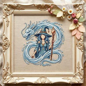 Könnte beinhalten: Eine Kreuzstichstickerei mit einer gesichtslosen Figur in blauem Hexenhut und Kleid, die einen Stab hält, umgeben von einem wirbelnden blauen Wasserdrachen. Das Kunstwerk befindet sich in einem verzierten, cremefarbenen Rahmen mit Goldakzenten.