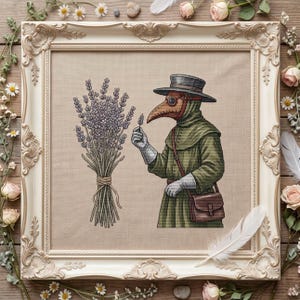Puede incluir: Un bordado en punto de cruz enmarcado que muestra a un médico de la peste con túnica verde con capucha y sombrero de ala ancha, usando una máscara marrón con forma de pájaro. La figura sostiene una ramita de lavanda junto a un ramo de lavanda.