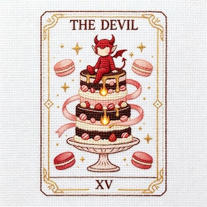 May include: Cross-stitch tarot card featuring a devil character atop a layered cake with macarons. The card is framed with gold accents and the text "THE DEVIL" and "XV". The devil is red with horns and a tail.