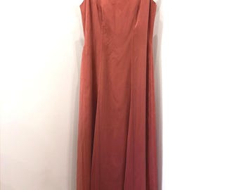 May include: A floor-length sleeveless dress in a solid terracotta orange color. The garment features a scoop neckline, wide shoulder straps, and a long, flowing skirt with vertical seam detailing that extends from the bodice to the hemline.