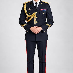 Könnte beinhalten: Eine dunkelmarineblaue Uniform im Militärstil mit einer Schirmmütze mit goldenem Emblem, einer Jacke mit goldenen Schulterklappen, goldenen geflochtenen Fangschnüren, goldenen Knöpfen, einer schwarzen Krawatte und einer Hose mit rotem Seitenstreifen.