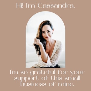 May include: A woman with long brown hair smiles at the camera. She is wearing a white lace top and a silver necklace. The text "Hi! I'm Cassandra. I'm so grateful for your support of this small business of mine." is displayed below the image.