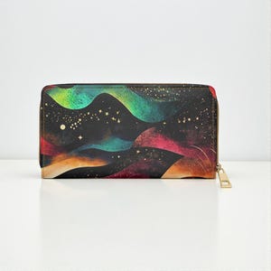 Puede incluir: Una cartera rectangular con un diseño abstracto y colorido. La cartera presenta un fondo negro con formas fluidas en tonos verdes, azules, rojos y naranjas, con detalles de estrellas doradas. Tiene un cierre de cremallera dorado.