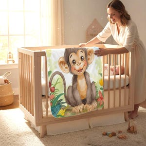 Könnte beinhalten: Eine Babydecke mit einer Illustration eines lächelnden Affen, umgeben von bunten Blumen und Blättern. Die Decke ist über ein Holzbettchen gelegt. Eine Frau in einem beigen Kleid ist in der Nähe zu sehen.