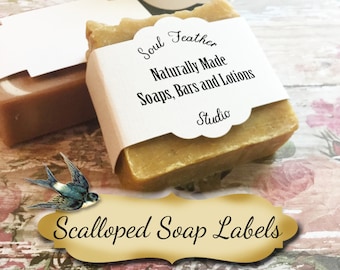 Peut inclure: Trois savons avec des étiquettes festonnées. Les étiquettes sont blanches avec du texte noir. Le texte sur l'étiquette indique "Soul Feather Naturally Made Soaps, Bars and Lotions Studio". Les savons sont sur une surface en bois avec un motif floral.