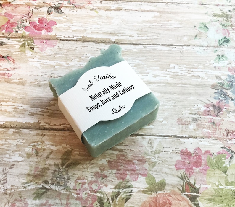 Puede incluir: Una barra cuadrada de jab&oacute;n azul claro con una etiqueta blanca que dice "Soul Feather Naturally Made Soaps, Bars and Lotions Studio".