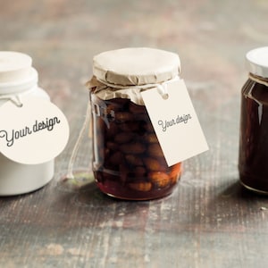 May include: Three glass jars with white lids and brown contents. Each jar has a white tag attached with the text "Your design" on it.