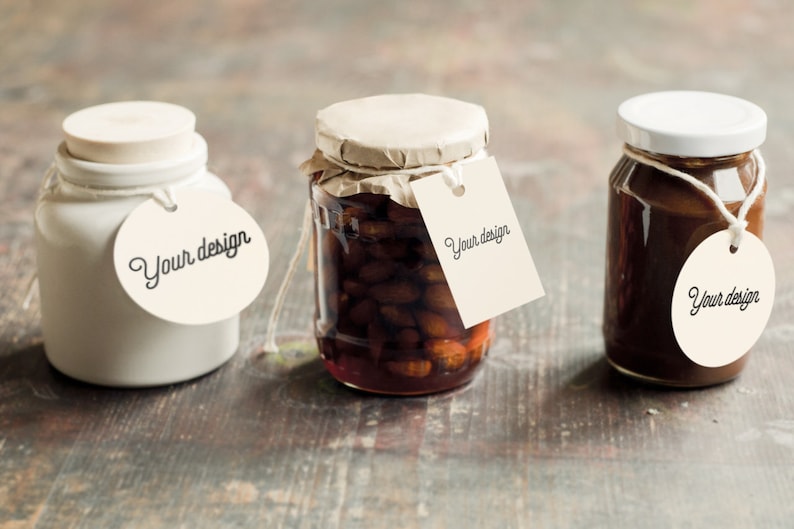 May include: Three glass jars with white lids and brown contents. Each jar has a white tag attached with the text "Your design" on it.