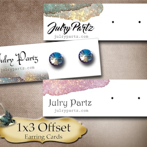 May include: 1x3 Offset Earring Cards with a watercolor background and glitter accents. The cards are white with two holes for displaying earrings. The text "Julry Partz" and "julrypartz.com" is printed on the cards.