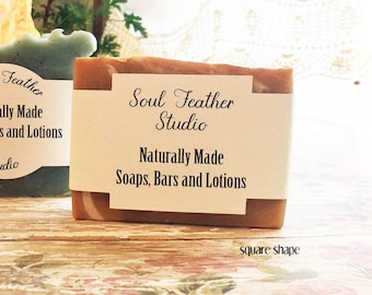 May include: Two bars of handmade soap, one is a light blue color and the other is a brown color with swirls. The brown soap has a label that reads "Soul Feather Studio" and "Naturally Made Soaps, Bars and Lotions".