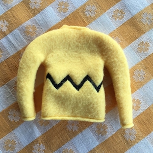 May include: A yellow fleece sweater with a black zig-zag pattern on the front.