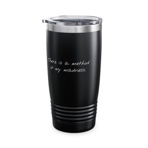 May include: Black insulated tumbler with a silver lid. The tumbler has the phrase "There is a method of my madness" in white script. The tumbler is cylindrical with a ridged bottom.