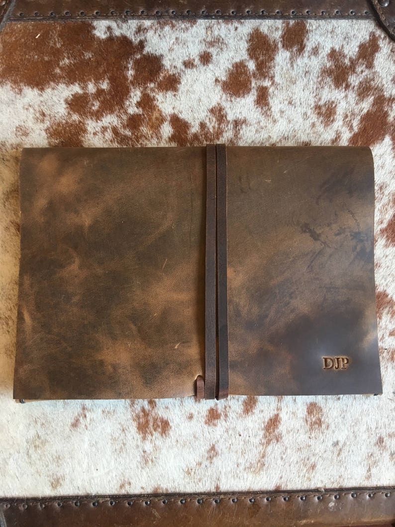 May include: A brown leather journal with a strap closure and the initials "DJP" embossed on the cover.
