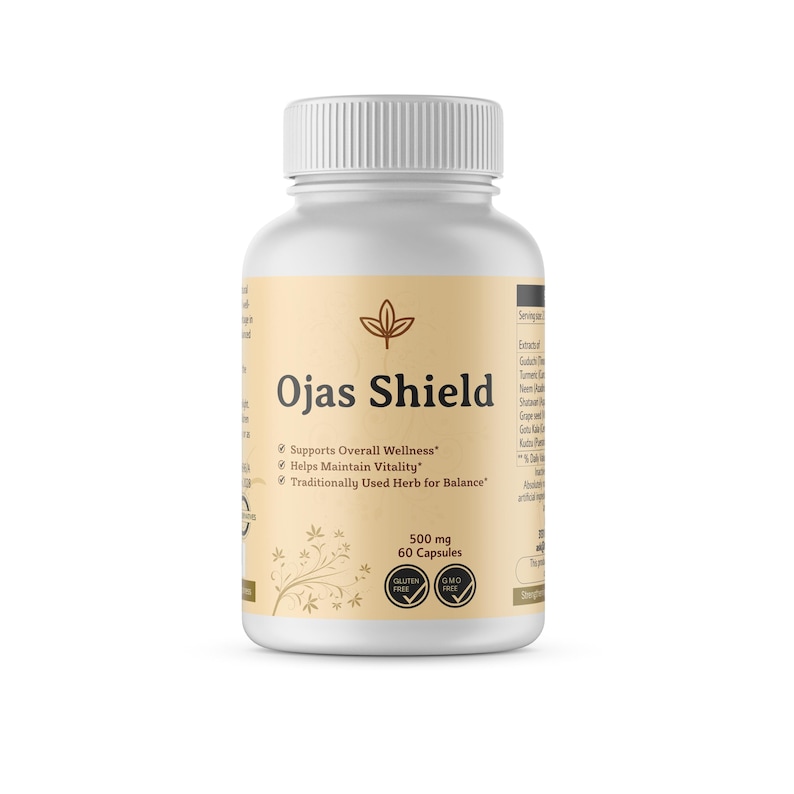 May include: A white plastic bottle of Ojas Shield capsules. The label is tan with the product name and the text "Supports Overall Wellness", "Helps Maintain Vitality", and "Traditionally Used Herb for Balance". The bottle contains 60 capsules, each 500 mg.