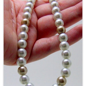 May include: A white pearl necklace with gold accents. The necklace is made of round pearls and is strung on a thin cord.