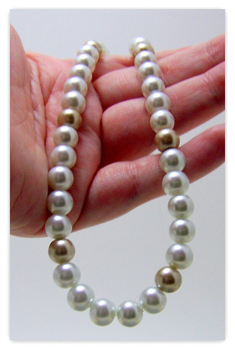 May include: A white pearl necklace with gold accents. The necklace is made of round pearls and is strung on a thin cord.