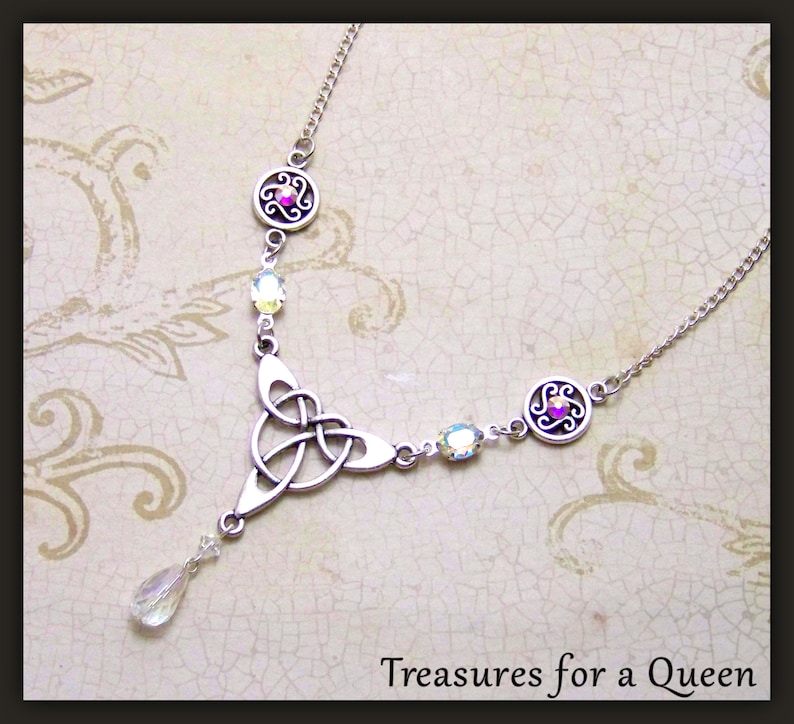 Puede incluir: Collar de plata con nudo celta, un colgante de cristal en forma de l&aacute;grima y detalles de cristal transparente. El collar presenta un dise&ntilde;o circular con una piedra rosa en el centro.