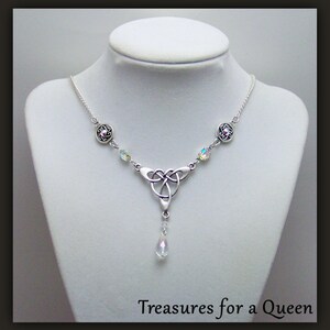 Puede incluir: Collar de plata con nudo celta, un colgante de cristal en forma de l&aacute;grima y detalles de cristal transparente. El collar tiene una cadena de plata y dos abalorios redondos de plata con un cristal rosa en el centro.