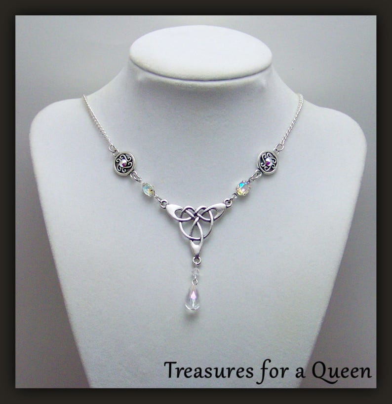 Puede incluir: Collar de plata con nudo celta, un colgante de cristal en forma de l&aacute;grima y detalles de cristal transparente. El collar tiene una cadena de plata y dos abalorios redondos de plata con un cristal rosa en el centro.