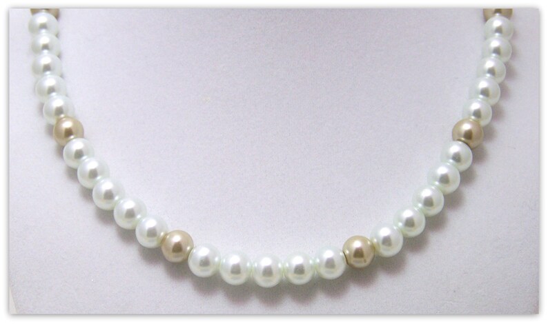 May include: A white pearl necklace with gold beads. The necklace is made of small, round pearls and gold beads.