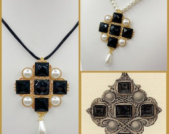 May include: A black and gold pendant necklace with a square-shaped design featuring black gemstones and white pearls. The pendant is attached to a black cord and has a single white pearl dangling from the bottom.