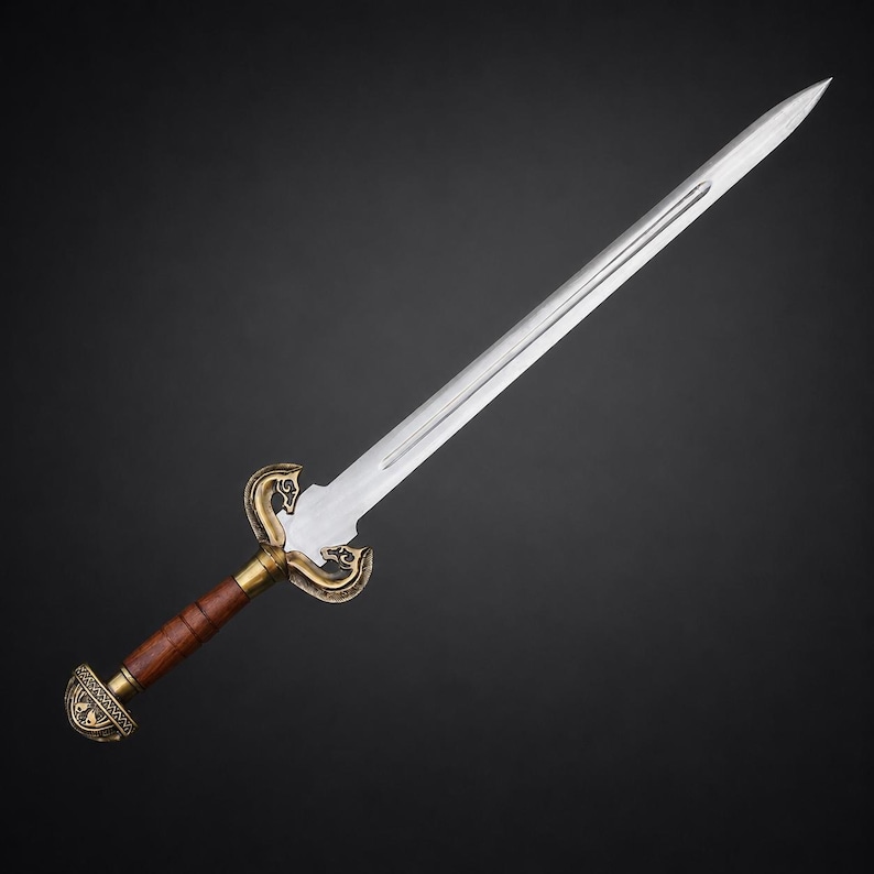 May include: A double-edged steel sword featuring a central fuller, a brass-toned crossguard with ornate scrollwork, a cylindrical brown wooden grip, and a matching brass-toned pommel with intricate engraved detailing on the base.