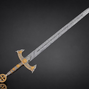 May include: A long sword featuring a Damascus steel blade with a distinct wavy pattern. The hilt is crafted from silver-toned metal with gold-colored accents, including a circular pommel with a cross design and a crossguard with ornate detailing.