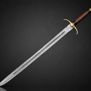May include: A sword with a patterned Damascus steel blade featuring a central fuller. The hilt includes a gold-colored crossguard, a black grip wrapped with thin red bands, and a gold-colored pommel cap at the end of the handle.