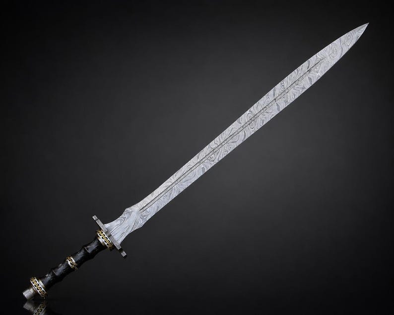 May include: A double-edged sword featuring a long, pointed blade with a distinct wavy, layered metal pattern. The handle is black with gold-colored metal accents at the pommel, grip, and crossguard, showcasing intricate decorative detailing.