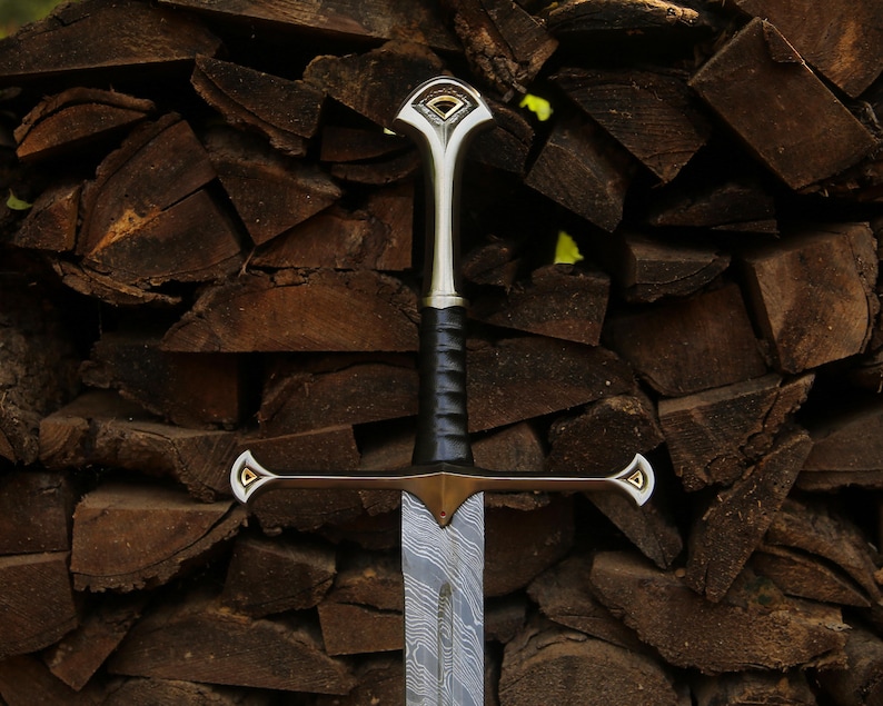 May include: A sword featuring a patterned Damascus steel blade, a black leather-wrapped grip, and a metallic crossguard and pommel. The crossguard and pommel are accented with gold-colored triangular inlays at the tips and center.