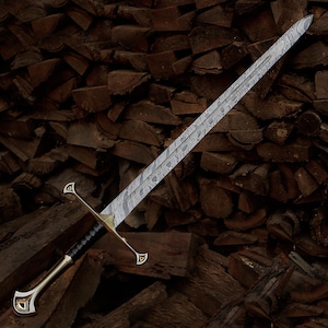 May include: A long sword featuring a double-edged blade with a distinct wavy, layered Damascus steel pattern. The hilt includes a metallic crossguard, a black wrapped grip, and a pommel with gold-colored accents at the base of the handle.