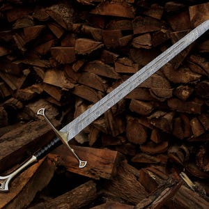 May include: A long sword featuring a double-edged blade with a distinct wavy Damascus steel pattern. The hilt includes a metallic crossguard with triangular accents, a black leather-wrapped grip, and a curved pommel with a metallic inlay detail.