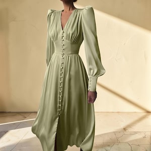 Puede incluir: Vestido midi verde salvia con escote en V y mangas largas. El vestido presenta una botonadura frontal, cintura entallada y una ligera abertura en la falda. Las mangas tienen pu&ntilde;os abotonados. El vestido est&aacute; hecho de una tela sedosa y fluida.