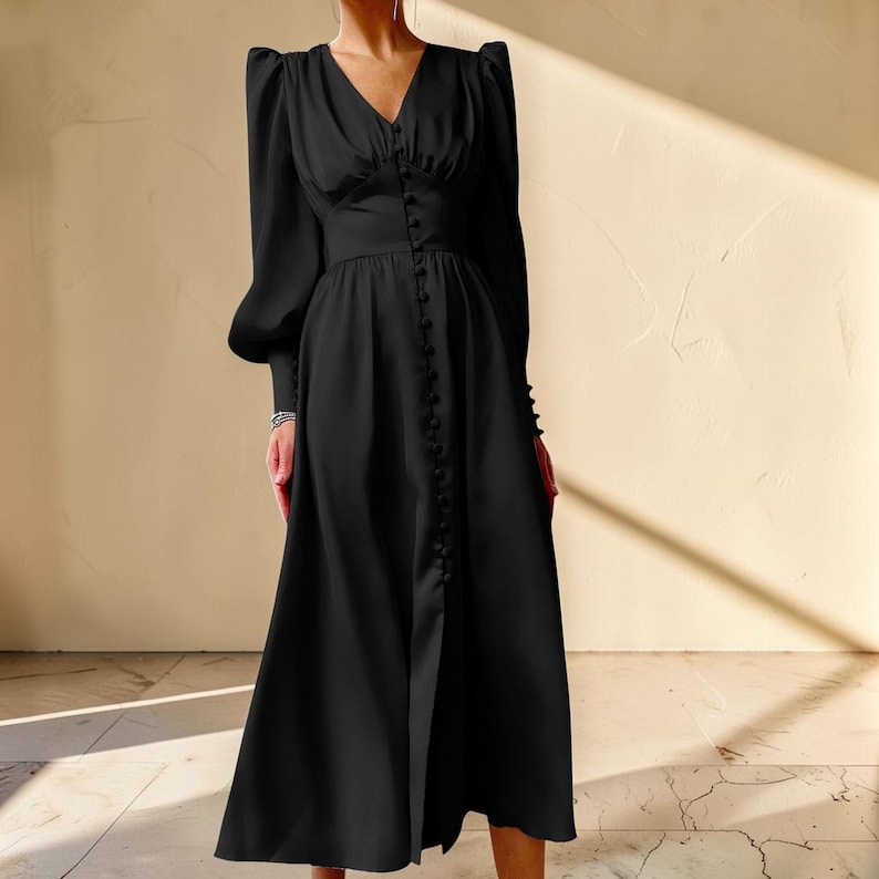 Puede incluir: Un vestido midi negro con escote en V y mangas largas. El vestido presenta una fila de botones en la parte delantera y una cintura entallada. Las mangas tienen un dise&ntilde;o de hombros abullonados. El vestido est&aacute; hecho de una tela suave y fluida.