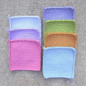 May include: A collection of seven square, hand-crocheted potholders arranged in two columns. The potholders feature a textured, woven-style stitch pattern and a small loop on one corner, appearing in shades of light blue, lavender, pink, green, and tan.