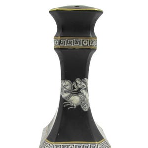 May include: Black decorative candlestick with gold trim and Greek key design. The candlestick features a white and gray illustration of a chariot pulled by horses. The candlestick is approximately 7 inches tall.