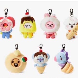 May include: A selection of plush keyrings with cartoon character designs. The keyrings depict a donut, pudding, bunny, sheep, and koala. Each character is brightly coloured and has a metal clasp for attaching to keys or bags.