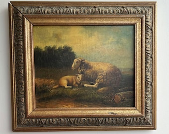 May include: An oil painting in a decorative gold-toned frame depicting a sheep and a lamb resting in a grassy field. The scene features a dark treeline in the background under a muted sky, with the signature J. Pajot visible in the lower right corner.