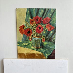 Könnte beinhalten: Ein Ölgemälde auf einer rechteckigen Leinwand, das einen Strauß leuchtend roter Mohnblumen in einer zylindrischen Vase zeigt. Die Vase steht auf einem gemusterten grünen Tuch vor einem Hintergrund aus drapiertem grünem Stoff, gemalt mit sichtbaren Pinselstrichen.