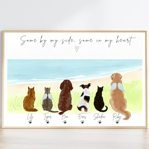 May include: A framed print depicting a beach scene with seven illustrated pets: a cat, a dog, and a cat with angel wings. The text "Some by my side, some in my heart" is written above. Each pet has a name below it.