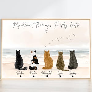 May include: A framed horizontal print featuring five cats sitting on a beach, facing the ocean. The text reads "My Heart Belongs To My Cats" above the cats, with the names "Shadow," "Patches," "Marmalade," "Tiger," and "Smokey" below each cat.