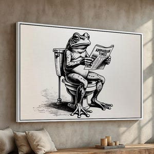 May include: Black and white framed art print featuring a frog sitting on a toilet, reading a newspaper titled "Amphibian Times." The artwork is a humorous illustration, perfect for a bathroom or novelty decor.