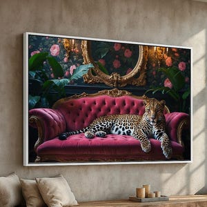 May include: A framed canvas print featuring a leopard resting on a pink velvet sofa. The sofa is set against a backdrop of floral wallpaper and a gold-framed mirror. The artwork is displayed above a wooden bench with pillows.