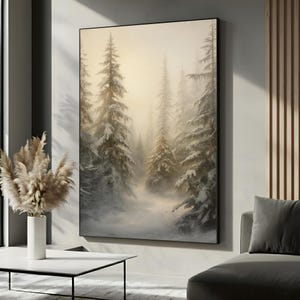 May include: A large framed canvas art print depicts a snowy forest scene. Tall evergreen trees are covered in snow, with a soft, diffused light filtering through the misty background. The artwork is displayed in a modern living room setting.