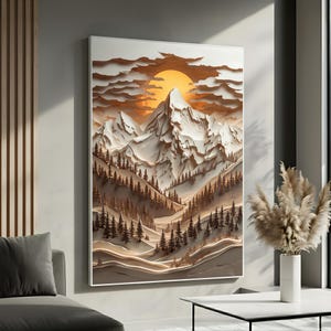 May include: A framed landscape art print featuring a mountain range with a setting sun. The artwork has a 3D effect with layered paper cutouts in shades of white, brown, and orange. The scene includes pine trees and rolling hills.