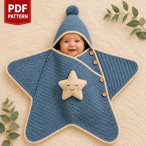 May include: A blue crocheted star-shaped baby swaddle blanket with a matching hood featuring a pom-pom. The swaddle has a cream-coloured trim, four wooden buttons along the side, and a small, smiling cream-coloured star appliqué on the front.