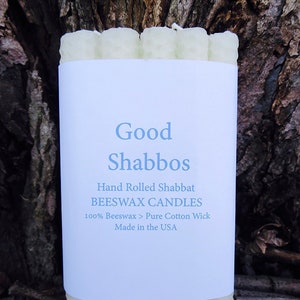 May include: A package of white beeswax candles with a label that reads "Good Shabbos", "Hand Rolled Shabbat Beeswax Candles", "100% Beeswax > Pure Cotton Wick", and "Made in the USA".